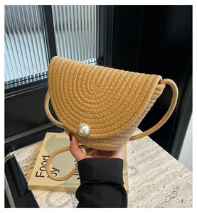 Detailed texture of semi-circular straw bag with large pearl buckle on marble surface