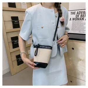 Vue détaillée du sac seau en toile avec finitions en cuir noir et bandoulière chic