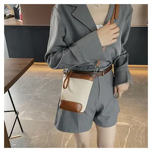 Détail du sac bandoulière en toile et cuir marron porté sur un tailleur gris chic