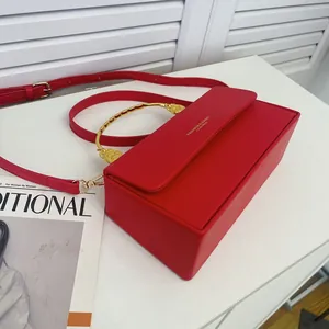 Sac boîte minimaliste en cuir rouge avec poignée dorée semi-circulaire et bandoulière réglable