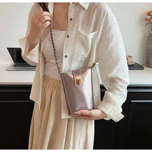 Détail de la bandoulière en chaîne et du fermoir doré sur un mini sac seau argenté