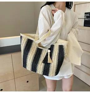Dettaglio della borsa tote in paglia a righe nere con nappine decorative