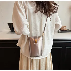 Détail du sac seau métallisé avec boucle dorée et bandoulière en chaîne