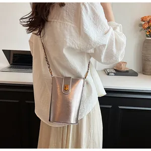 Petit sac seau argenté avec finition métallique et fermoir doré posé sur un bureau