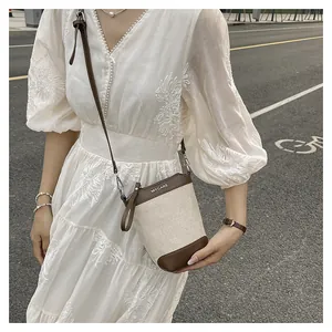 Détail du sac seau en toile et cuir avec logo MYCARE porté sur une robe en dentelle