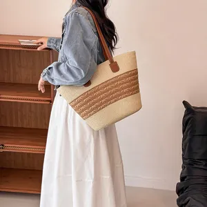 Handmade woven straw tote bag with brown leather straps worn by model for summer vacation