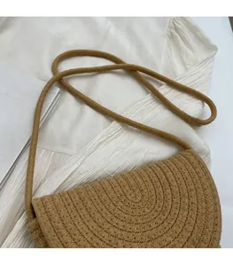 Detailed close-up of woven concentric texture on a khaki straw bucket bag with thin strap