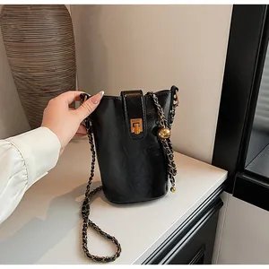 Détail d'un sac seau noir avec bandoulière en chaîne dorée et bille métal ajustable