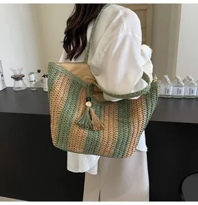 Dettaglio di una borsa tote intrecciata a righe con nappa e texture fatta a mano