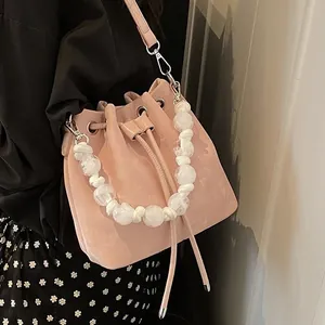 Pink matte drawstring bucket bag with pearl woven handle and leather shoulder strap