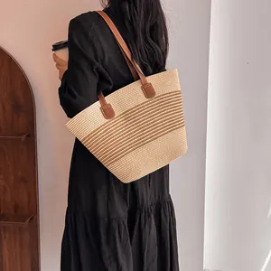Handmade woven straw tote bag with brown leather handles and striped texture for summer