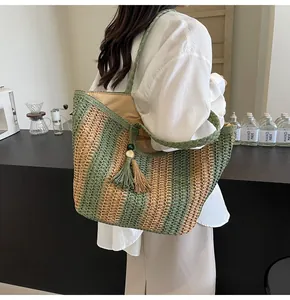 Dettaglio ravvicinato di una borsa tote in paglia a righe verdi con nappe decorative