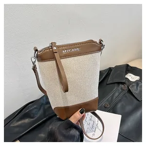 Détail du sac seau en toile avec bordure en cuir marron et logo Mycare porté à la main