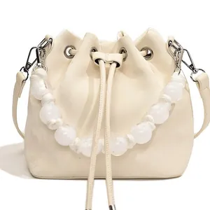 Minimalist cream white drawstring bucket bag with beaded handle and leather shoulder strap