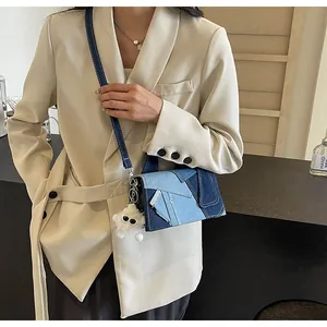 Detail of denim patchwork shoulder bag with unique geometric patterns and plush pendant