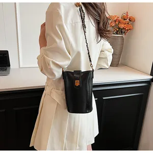 Détail d'un mini sac seau noir en cuir avec bandoulière chaîne dorée et fermoir rétro