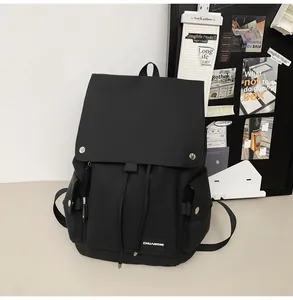 Detail of a minimalist black backpack featuring a flap cover and white woven brand label