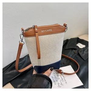 Détail d'un sac seau en toile avec garniture en cuir marron et base contrastée bleu marine