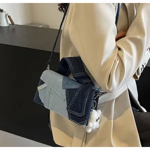 Detail of denim patchwork crossbody bag with plush charm and adjustable shoulder strap