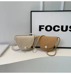 Detail of woven straw bucket bags in beige and camel with elegant pearl closure detail