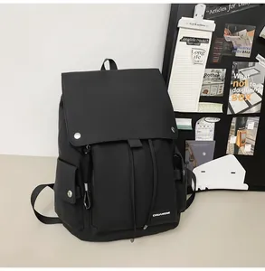 Detail of black nylon backpack featuring flap cover and metallic snap button closures