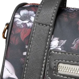 Detail of floral fabric with lychee leather strap and bronze D-ring on skull handbag