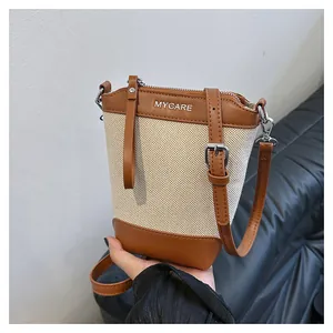 Détail du sac seau en toile beige et cuir marron avec logo MYCARE et fermeture à glissière