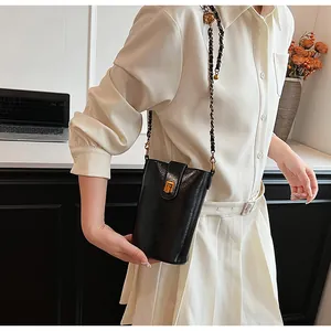 Mini sac bandoulière noir chic avec chaîne dorée présenté dans un décor de bureau