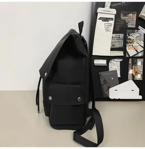 Detailed side view of black minimalist backpack with matte finish and secure metal snap buttons