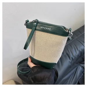 Détail du sac seau en toile et cuir vert avec logo MYCARE en métal et bandoulière
