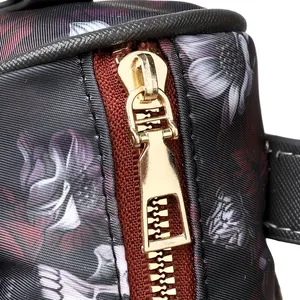 Macro shot of metallic gold zipper and dark floral print on durable handbag fabric