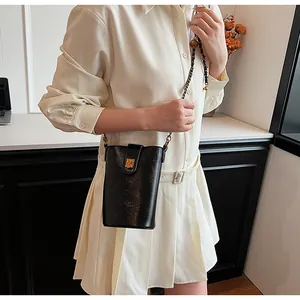 Détail d'un mini sac bandoulière noir élégant avec chaîne dorée porté par un mannequin