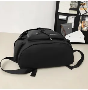 Detail of a black nylon backpack featuring drawstring closure and functional front pocket