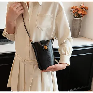Détail d'un mini sac bandoulière noir avec fermoir rotatif doré et bandoulière chaîne