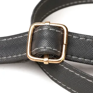 Detail of black Saffiano leather strap with white contrast stitching and gold buckle
