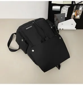 Detail of minimalist black nylon backpack featuring drawstring closure and metal snaps