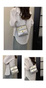 Detail van een zilveren metallic crossbodytas met gouden draaisluitingen