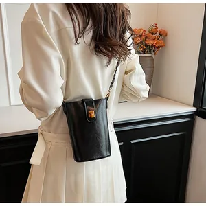 Détail du sac cylindre noir avec boucle magnétique dorée et bandoulière en chaîne