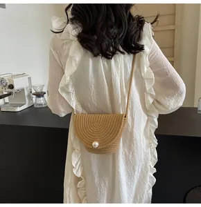 Detail of straw bucket bag featuring a large pearl button and woven texture on model