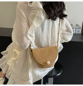 Detail of hand-woven straw bucket bag with large pearl closure on white summer dress