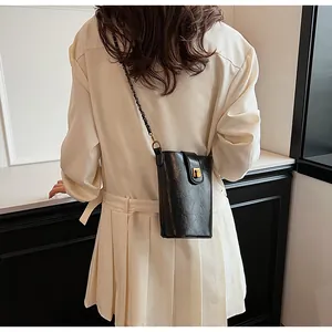 Détail du mini sac à bandoulière en cuir noir avec chaîne dorée et fermoir métallique