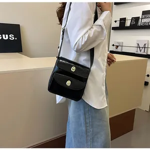 Detailweergave van de zwarte glanzende crossbodytas met twee zakken en gouden sloten
