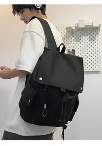 Detail view of the black nylon backpack side pocket with drawstring and silver buckle