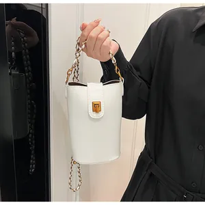 Détail du sac seau blanc avec un fermoir doré et une bandoulière en chaîne tressée