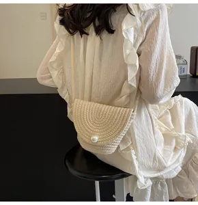 Detail of straw bucket bag featuring a large pearl buckle and spiral woven texture