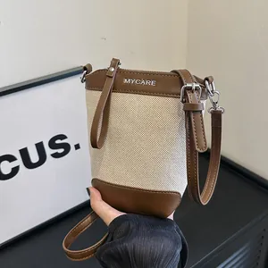 Sac seau bandoulière chic en toile beige et cuir marron avec bandoulière réglable