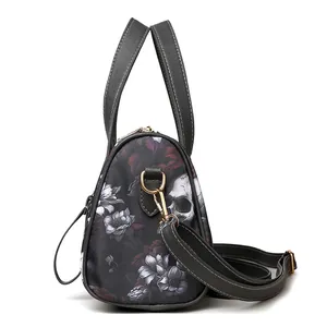 Close-up of gothic skull floral print Boston bag with textured leather strap and gold hardware
