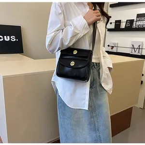 Detail van de zwarte crossbodytas met dubbele lagen en gouden metalen draaisluitingen