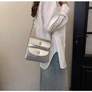 Detail van zilveren matte crossbody tas met vintage gouden draaisluitingen