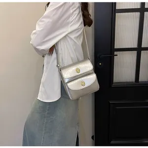 Detail van zilveren crossbodytas met dubbele draaisluitingen en geplisseerd leer